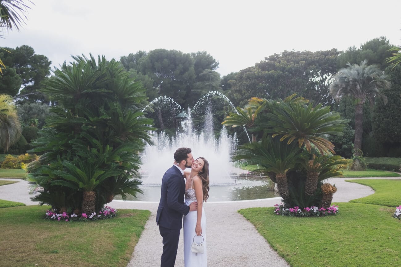 Kissing in Villa Ephrussi garden, with fountains in the backdrop to celebrate their engagement