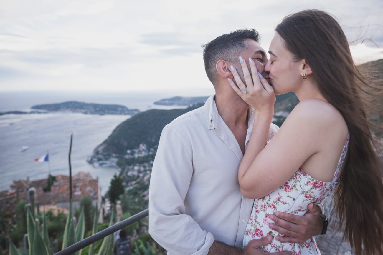 The couple embracing and kissing just after saying yes, with the wind blowing through her hair.